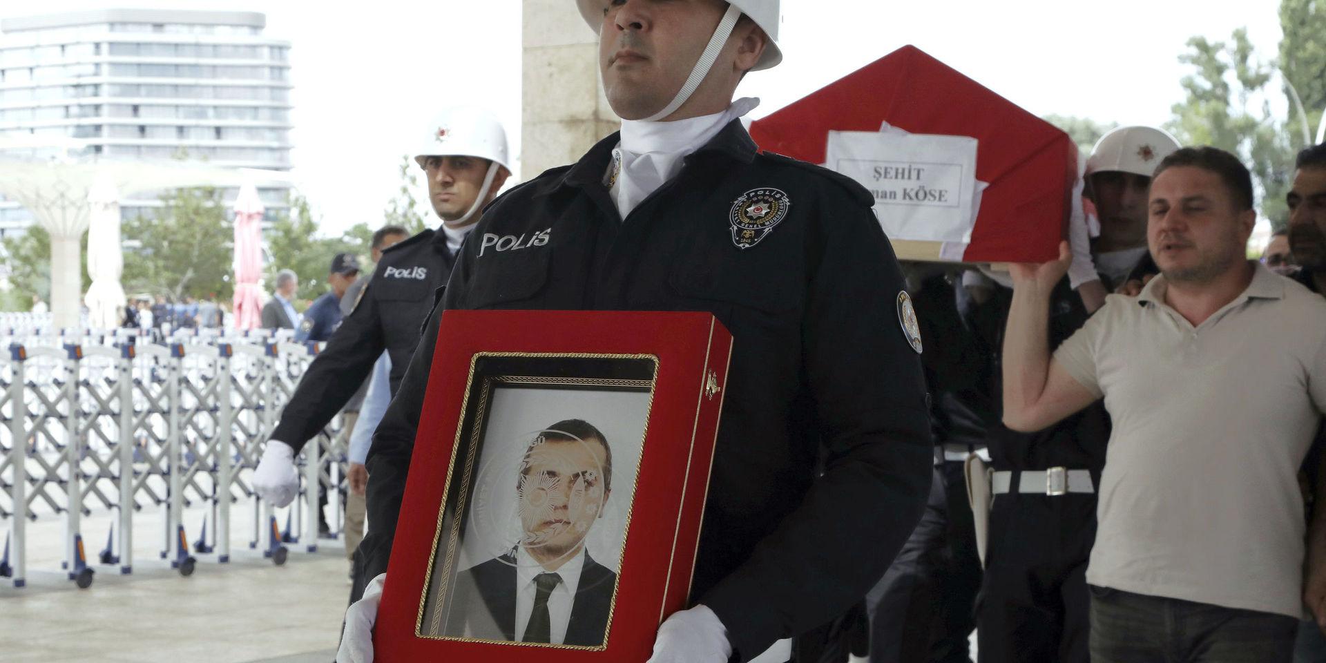 En polis bär en bild av den turkiske diplomaten Osman Köse som mördades i Erbil i Irak inför begravningen i Turkiets huvudstad Ankara.