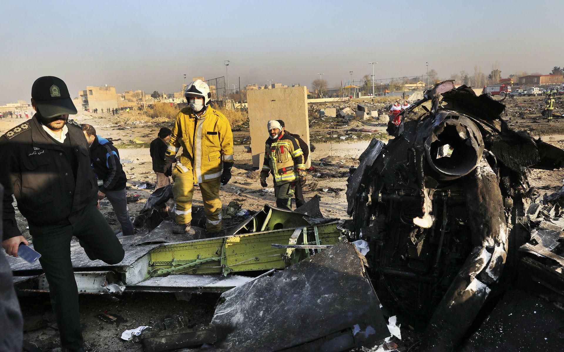 Räddningsarbetare går runt i den stora förödelsen efter flygkraschen i Iran.