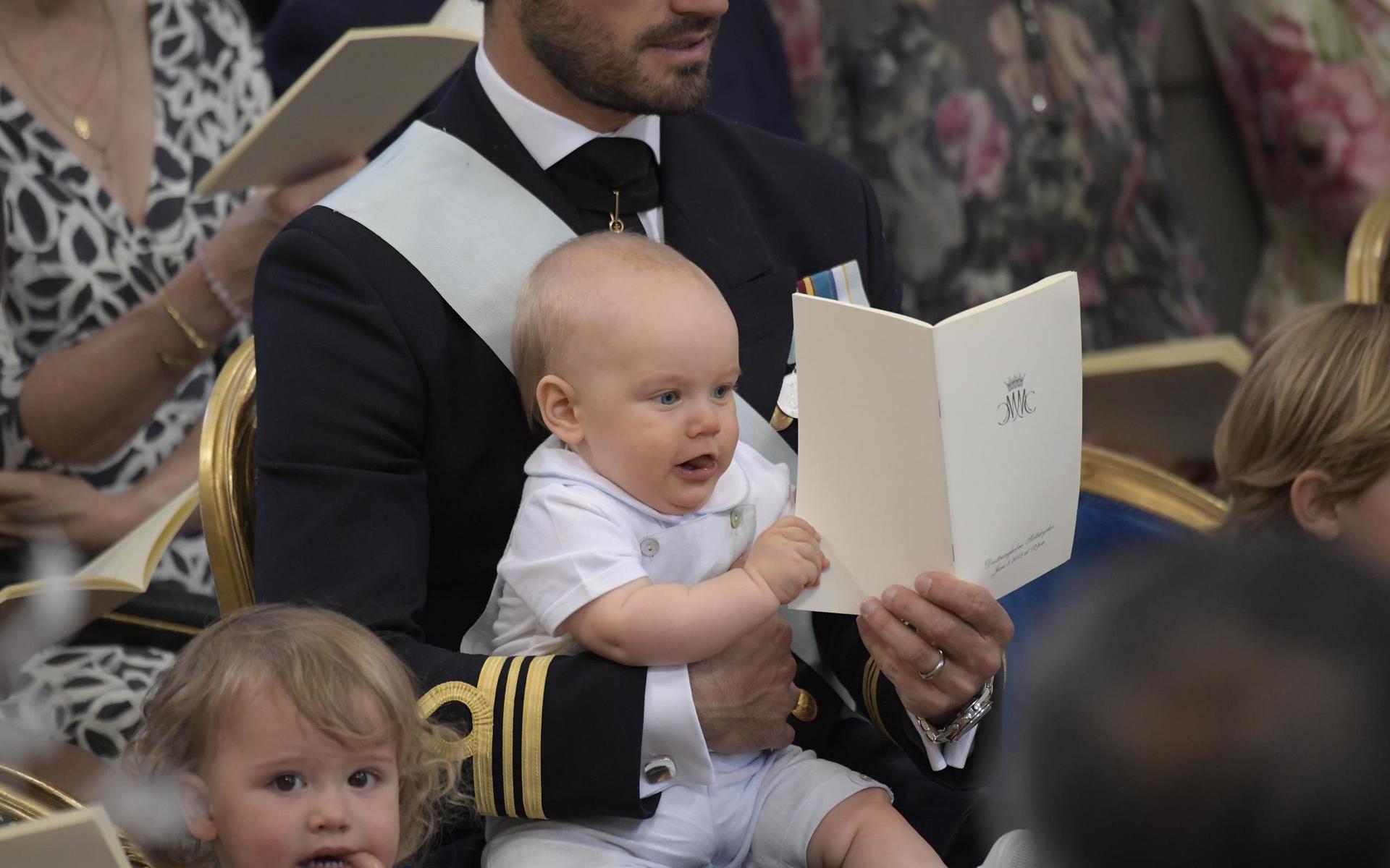 Prins Carl Philip med prins Gabriel som vill vara med och sjunga när hans kusin, prinsessan Adrienne döptes 2018. Längst ner till vänster syns storebror prins Alexander. Arkivbild.