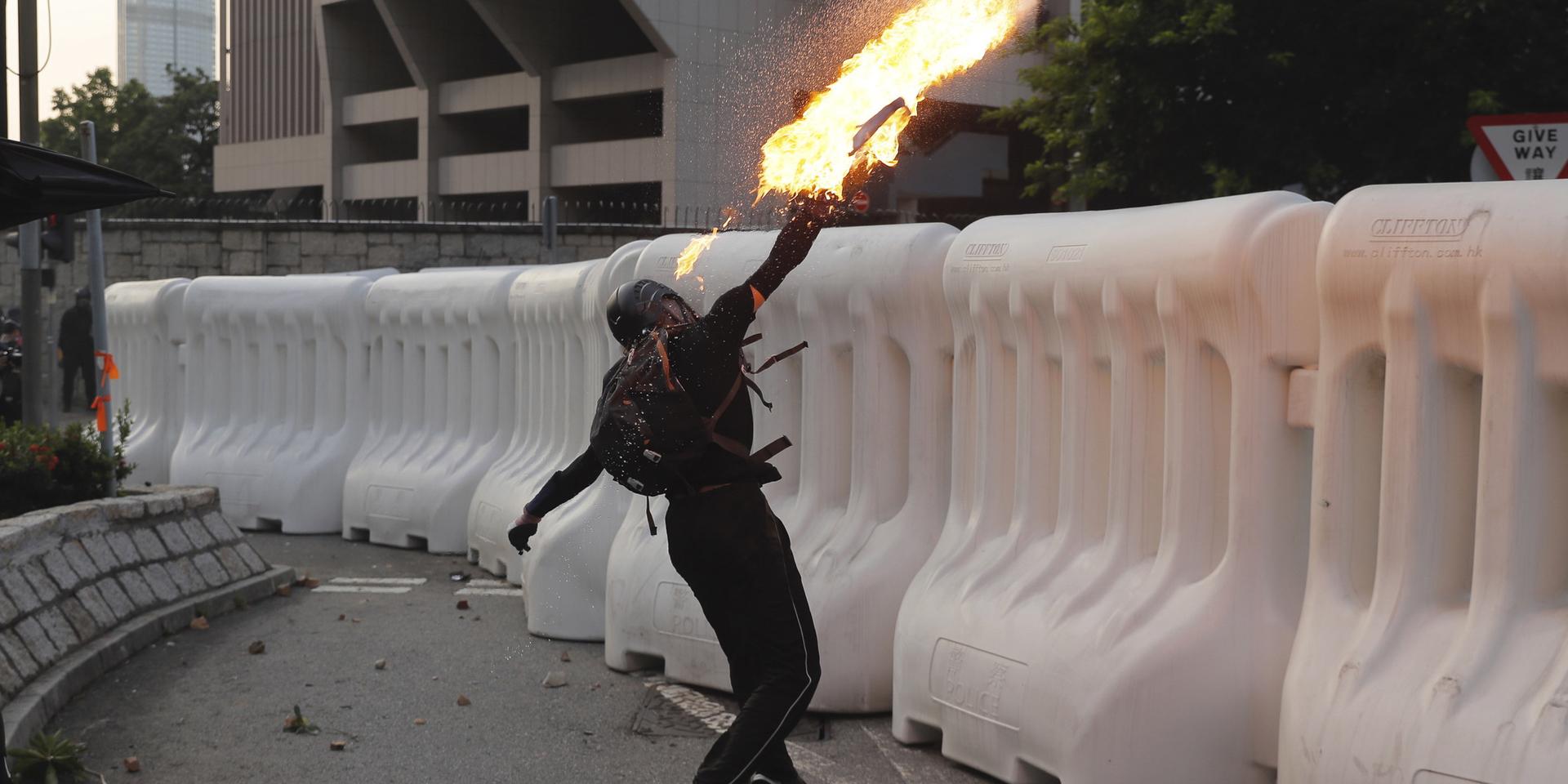 En av de protesterande Hongkongborna kastar en bensinbomb under söndagen. Delar av demonstrationen urartade i våldsamheter.