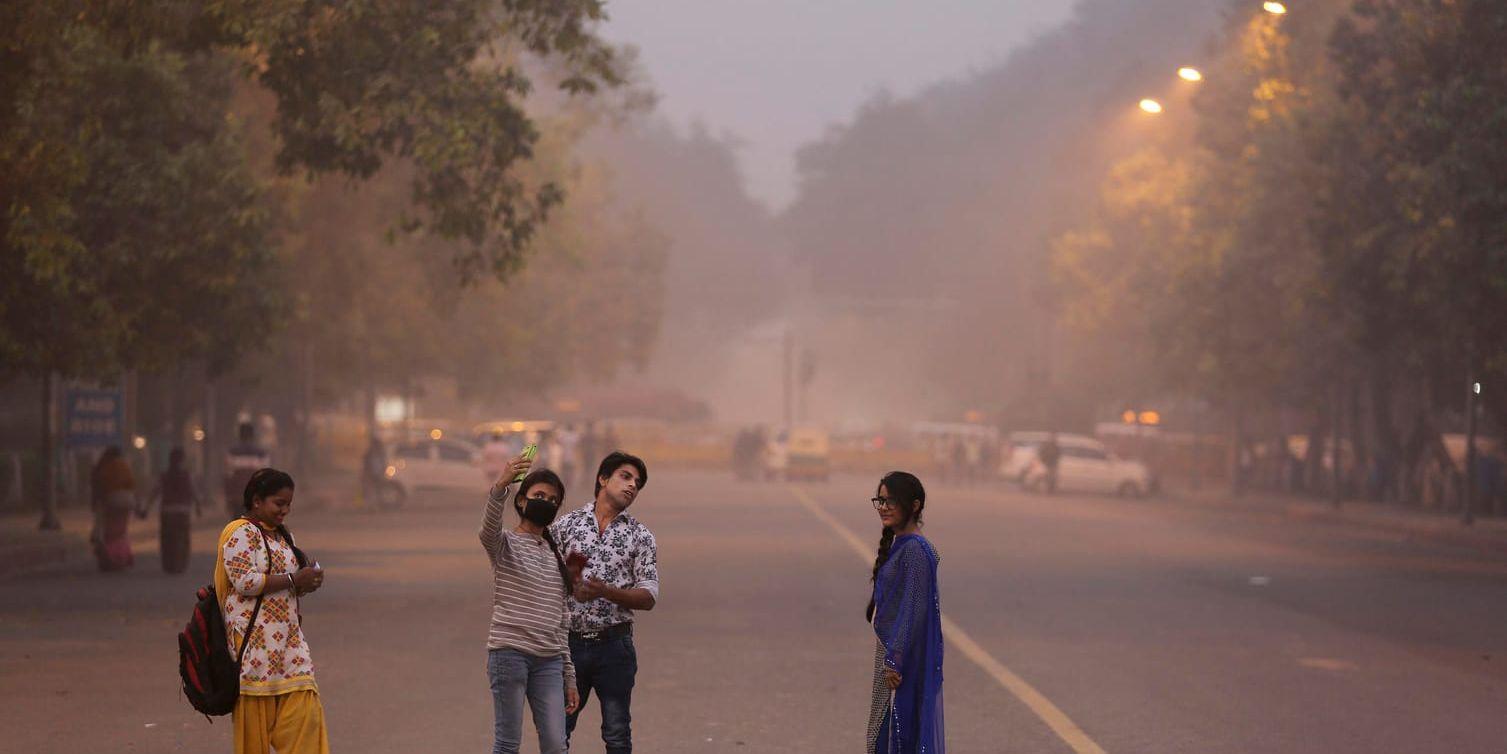 En flicka med munskydd tar en selfie i smogen i Delhi i tidigare i november.