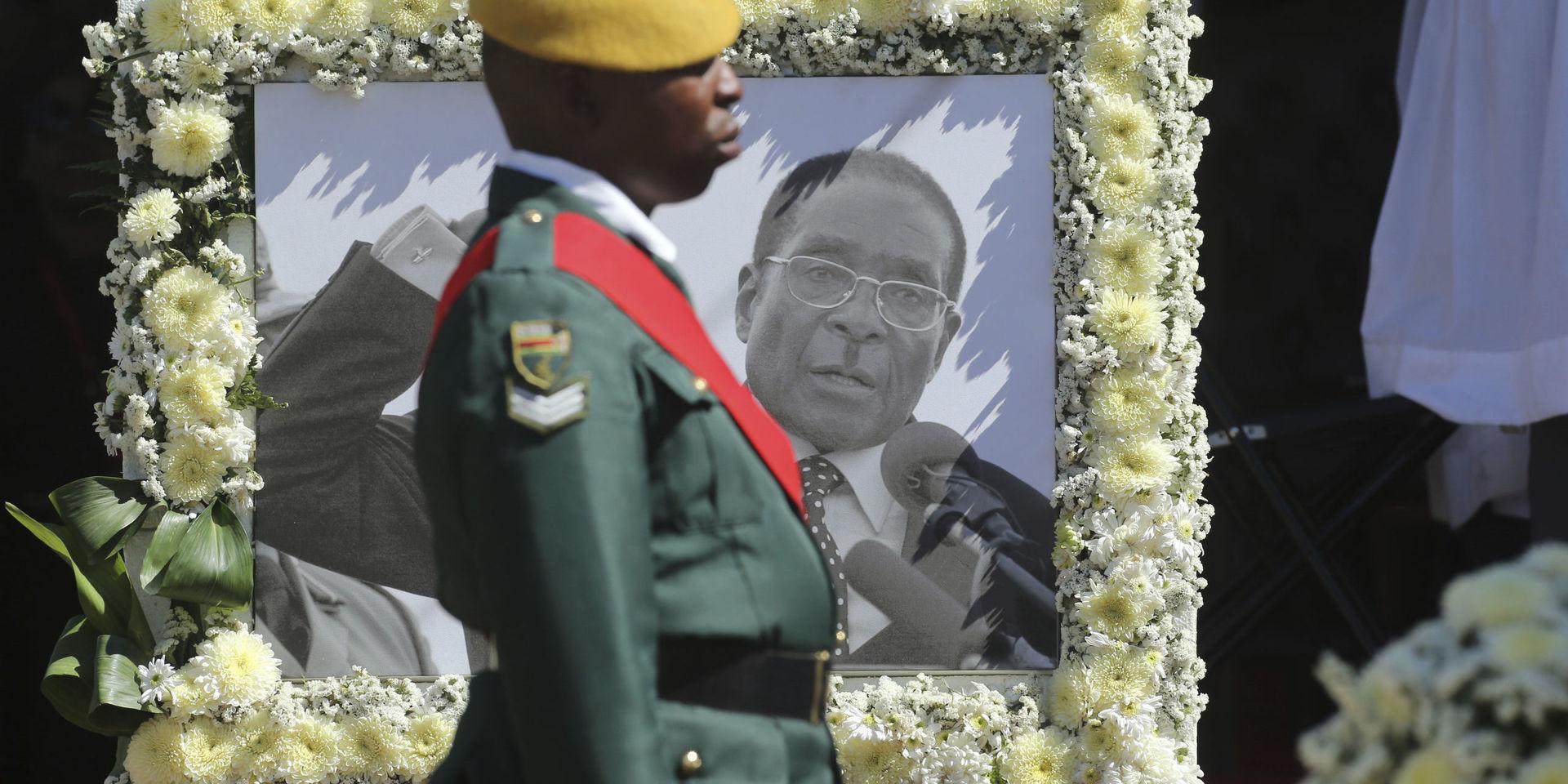 En soldat vid ett porträtt av den tidigare presidenten Robert Mugabe vid begravningen i höstas. Arkivbild. 