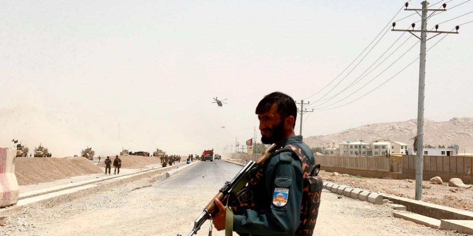 En afghansk polis står vakt i närheten av den plats där en självmordsbombare körde in i en Nato-konvoj i Kandahar.