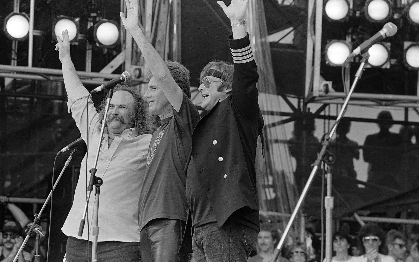 David Crosby, Graham Nash och Stephen Stills vinkar till publiken under deras konsert på JFK Stadium i Philadelphia 1985.