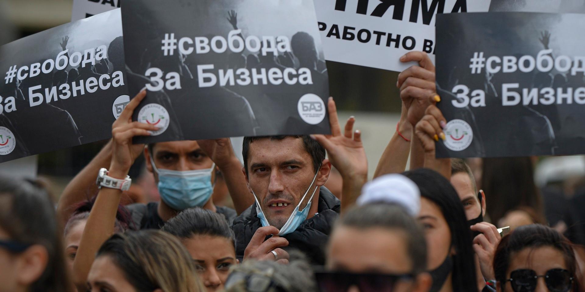 Demonstranter håller upp plakat med texten ”frihet för företag” och ”covid-19 finns inte” under en demonstration i Veliko Tarnovo, Bulgarien i september.