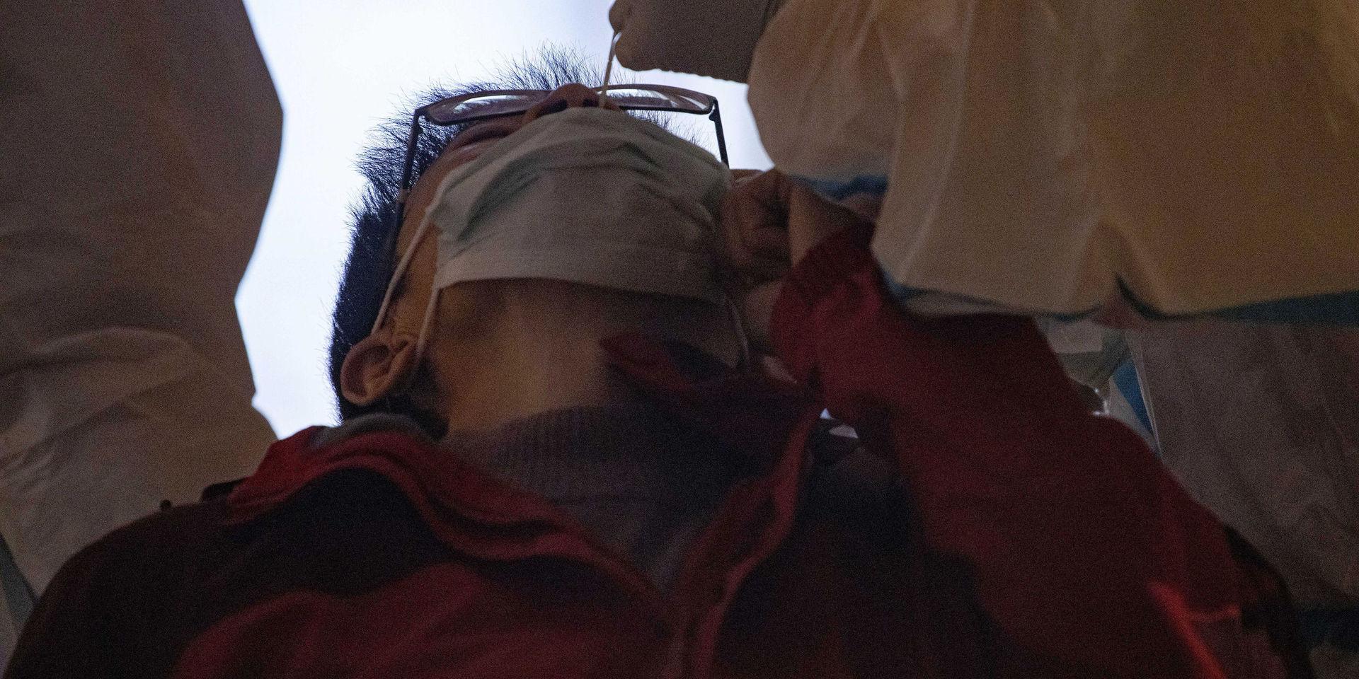 En man testas med en bomullspinne på ett karantänsboende i Wuhan på tisdagen.