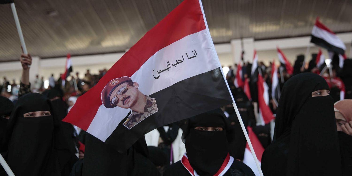En jemenitisk kvinna håller en flagga med Ahmed Ali och texten "Jag älskar Jemen" på arabiska. Arkivbild.
