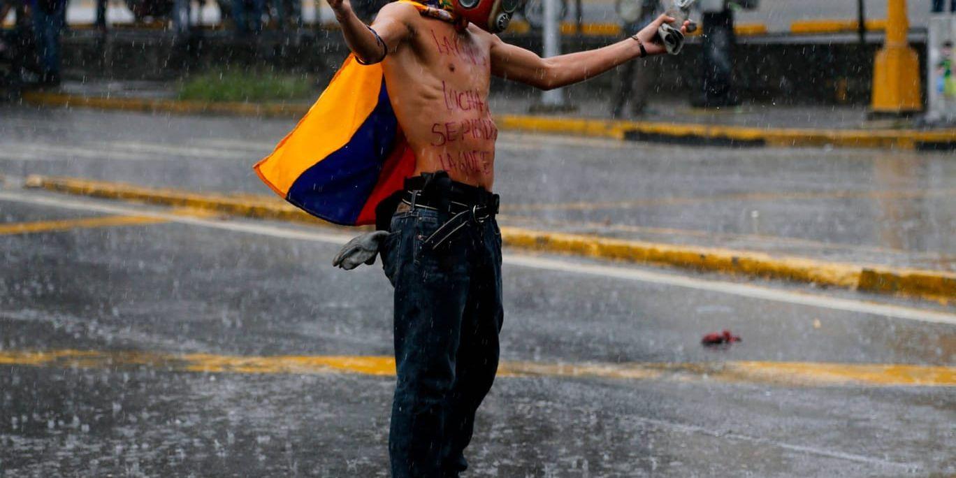 En man demonstrerar mot regeringen i regnet i Caracas, Venezuela.