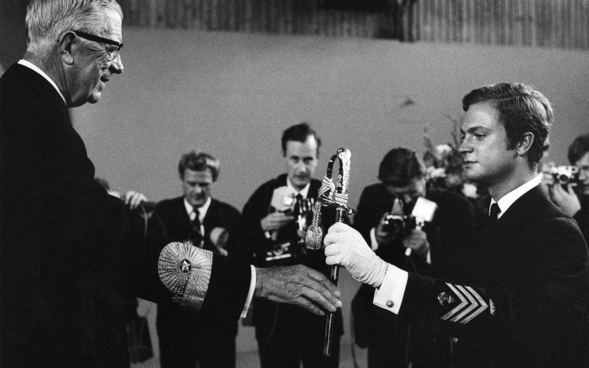 Kronprins Carl Gustaf tar emot en hederssabel av sin farfar kung Gustaf VI Adolf vid officerexamenceremonin där kronprinsen blev fänrik tredubbelt, i flottan, flygvapnet och armén på onsdagen 11:e september 1968.