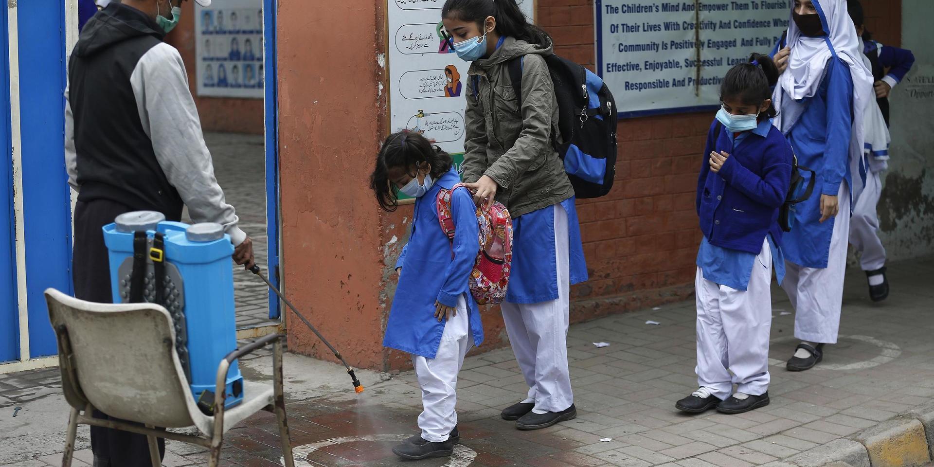 Elever får sina skor desinfekterade i Lahore i Pakistan på onsdagen.