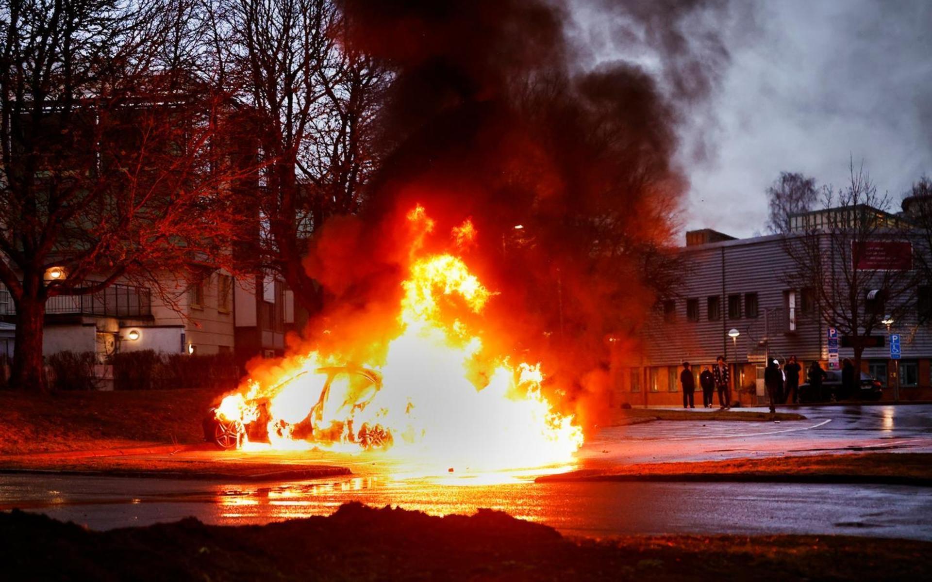 En bil brinner på en parkering i samband med upplopp i Navesta i Norrköping på torsdagskvällen. Nu vill högerextremisten Rasmus Paludan göra ett nytt försök där. Bild: 