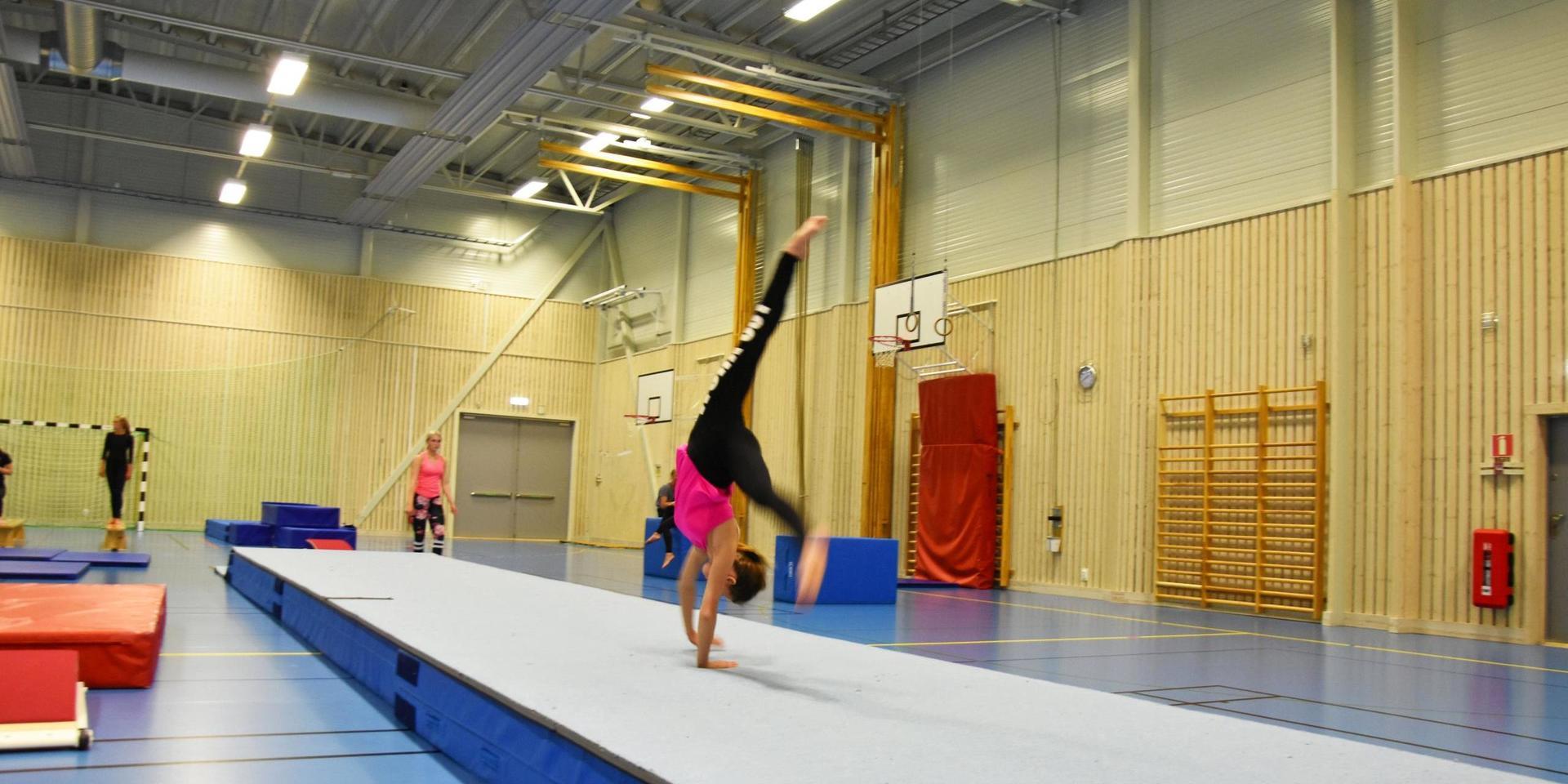 En gymnast står på händer på en matta